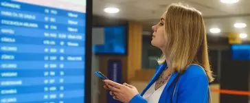 Female passenger in the airport lounge at the timetable