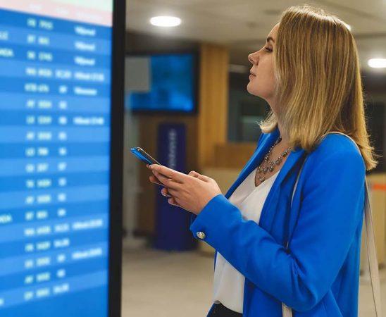 Female passenger in the airport lounge at the timetable