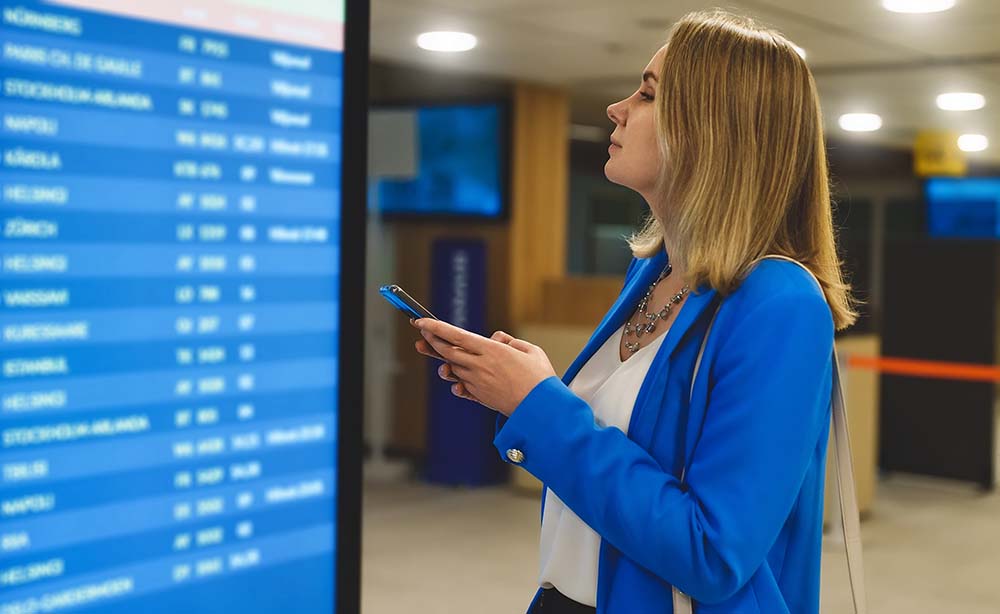 Female passenger in the airport lounge at the timetable