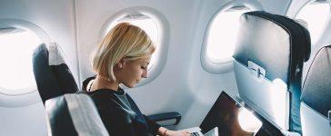 Woman with laptop and mobile phone in the airplane.