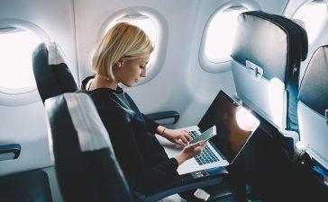 Woman with laptop and mobile phone in the airplane.