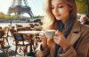 A young female tasting a croissant and cappuccino in Paris, France.